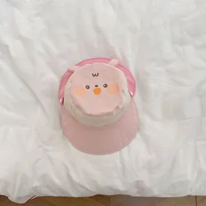Detail of pink and beige baby sun hat with cute cartoon face and soft 3D animal ears