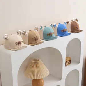 Detalle de gorras de oso transpirables para bebé en beige, azul y caqui en estante
