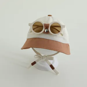 Dettaglio cappello sole neonato con tessuto a rete e occhiali retrò su supporto