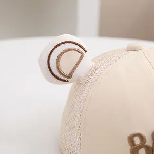 Detalle de gorra de malla para bebé con orejas de oso y bordado del número 8