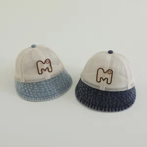 Close-up of baby sun hats featuring breathable mesh and denim brim with M smiley patch