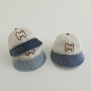 Detailed view of mesh baby sun hats featuring denim brims and smiling letter M embroidery
