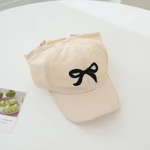 Detailed view of beige sun hat with black embroidered bow and wide stitched brim