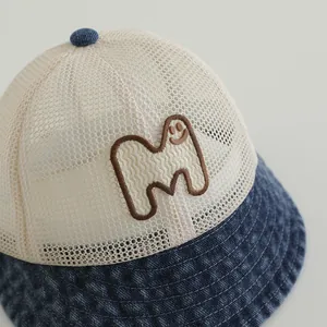 Detailed close-up of a kids mesh truck hat featuring a denim brim and smile M embroidery