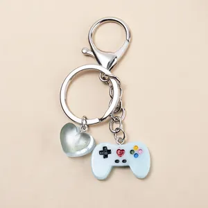 Primer plano de un llavero de mini mando de juego azul con un dije de corazón verde