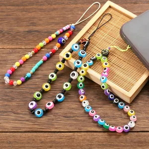 Colorful Evil Eye phone charms with polymer clay and beads on a wooden background