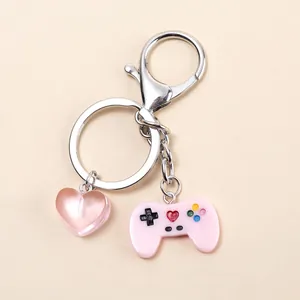 Detalle de colgante de mando de juego rosa y corazón en llavero plateado