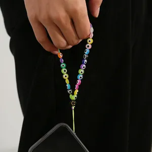 Close-up of colorful evil eye beaded phone strap with a gold smiley face bead detail