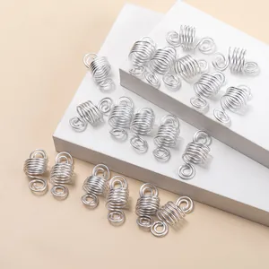 Anneaux de cheveux en spirale argentée pour dreadlocks sur surface texturée blanche