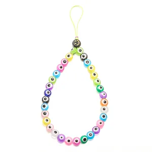 Close-up of colorful evil eye beads and a black smiley face charm on a phone lanyard
