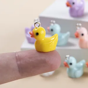 Mini resin duck pendants in candy colors for DIY jewelry making shown on fingertip
