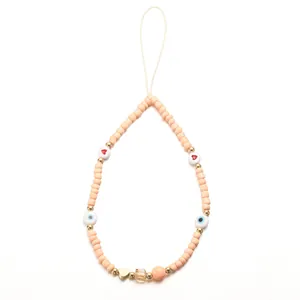 Detail of pink evil eye beaded phone strap with gold heart charm and peach beads