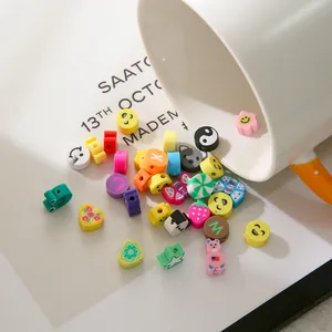 Nahaufnahme bunter 6mm Polymerton-Perlen mit Smileys und Buchstaben, die aus einer Tasse fallen