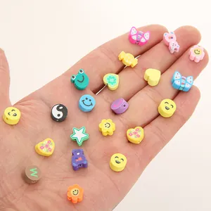 Nahaufnahme bunter Polymer-Ton-Perlen in der Hand mit Sternen, Herzen und Blumenformen