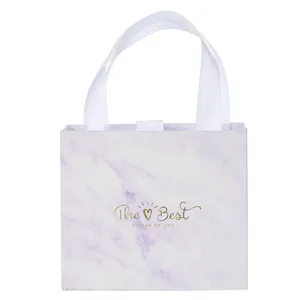 Detail der lila Marmor-Geschenktüte mit Goldtext und weißen Satin-Griffen