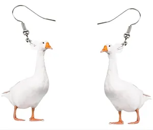 Detail of creative acrylic white goose drop earrings with orange beak and silver hooks