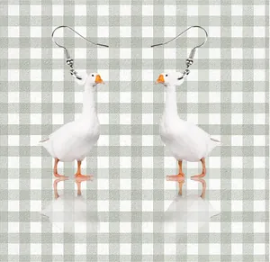 Detail shot of funny 2D acrylic white goose earrings with realistic feathers and orange beak