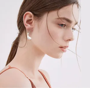 Close-up of creative acrylic white duck earrings with orange beak on a female model