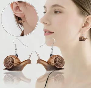 Macro shot of realistic acrylic snail earrings with detailed texture and silver hooks