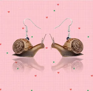 Detail view of realistic snail acrylic earrings with silver hooks on a pink checkered background
