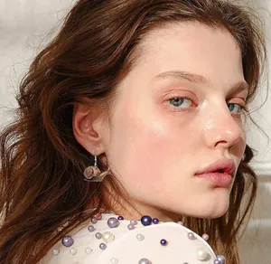 Detailed close-up of creative acrylic snail earrings worn by a model in soft lighting