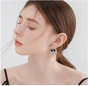 Close-up of creative acrylic cow pendant earring worn by a model in a natural setting