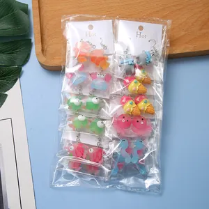 Flat lay of creative acrylic animal earrings set in clear packaging on a blue background