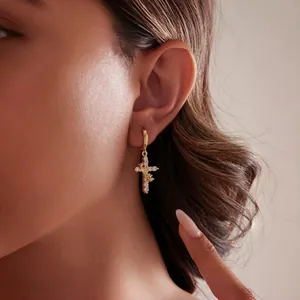 Elegant gold cross pendant necklace with zircon crystals worn by a female model