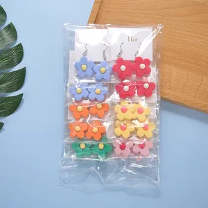 Detailed set of colorful resin flower earrings with metal hooks in clear packaging