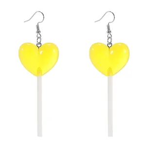 Close-up of heart-shaped yellow resin lollipop drop earrings with silver ear hooks