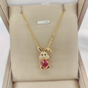Detail view of 14K gold plated rabbit pendant with red zircon stone on silk padding
