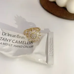 Adjustable golden sunflower ring with sparkling zircon petals on a white background