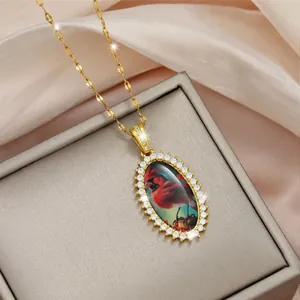 Collana ovale dorata con ciondolo uccello cardinale e bordo in zirconi brillanti