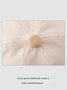 Close-up of beige kids baseball cap showing twill cotton texture and top button detail