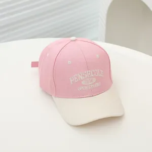 Detail of embroidered 1995 lettering on pink and beige kids cotton baseball cap