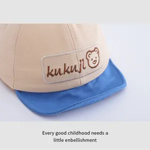 Dettaglio della toppa ricamata con orsetto kukuji su cappellino neonato beige