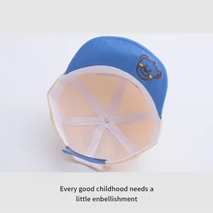 Dettaglio cappellino neonato con cinturino in velcro blu e ricamo orsetto decorativo