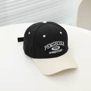 Detail of embroidered PENSECOLE 1995 letters on a two-tone black and white baseball cap