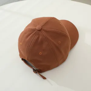 Vista detallada de la gorra marrón de algodón con correa ajustable y hebilla metálica