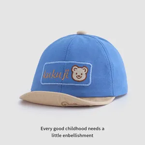 Dettaglio cappellino azzurro per neonati con ricamo a orsetto e visiera morbida beige