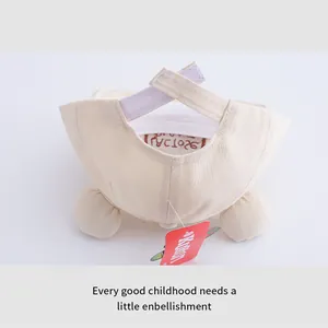 Dettaglio del cappellino beige per neonati con cinturino in velcro e orecchie di orso