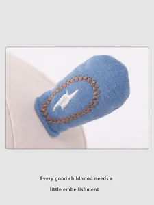 Detailed close-up of cute 3D bunny ear decoration with embroidery on a beige cotton hat