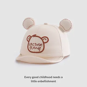 Dettaglio del cappellino neonato crema con orecchie di orso 3D e ricamo marrone