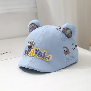 Close-up of light blue baby cap with bear patch and 3D mesh ears in a cozy setting