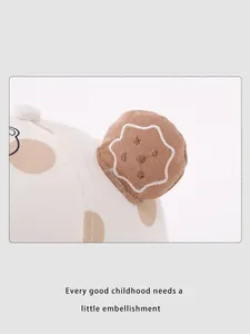 Close-up of beige cotton baby hat featuring brown polka dots and a 3D cookie embroidery