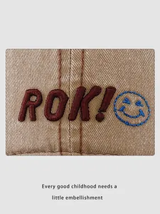 Detailed view of ROK! letter embroidery and blue smiley face on canvas kid baseball cap