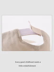 Detail of adjustable velcro strap on beige cotton baby baseball cap with neat stitching