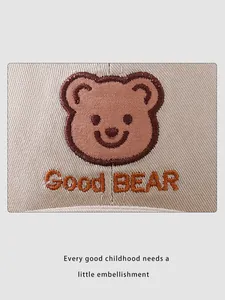 Close-up of brown cartoon bear embroidery and Good BEAR text on cotton baby cap