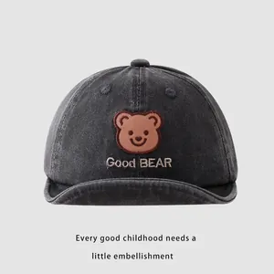 Detailed view of the dark grey bear embroidery and text on a baby sun hat