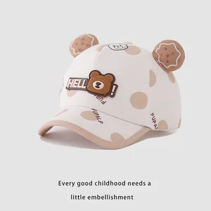 Detail of cream baby baseball cap with bear ears, brown polka dots, and HELLO patch